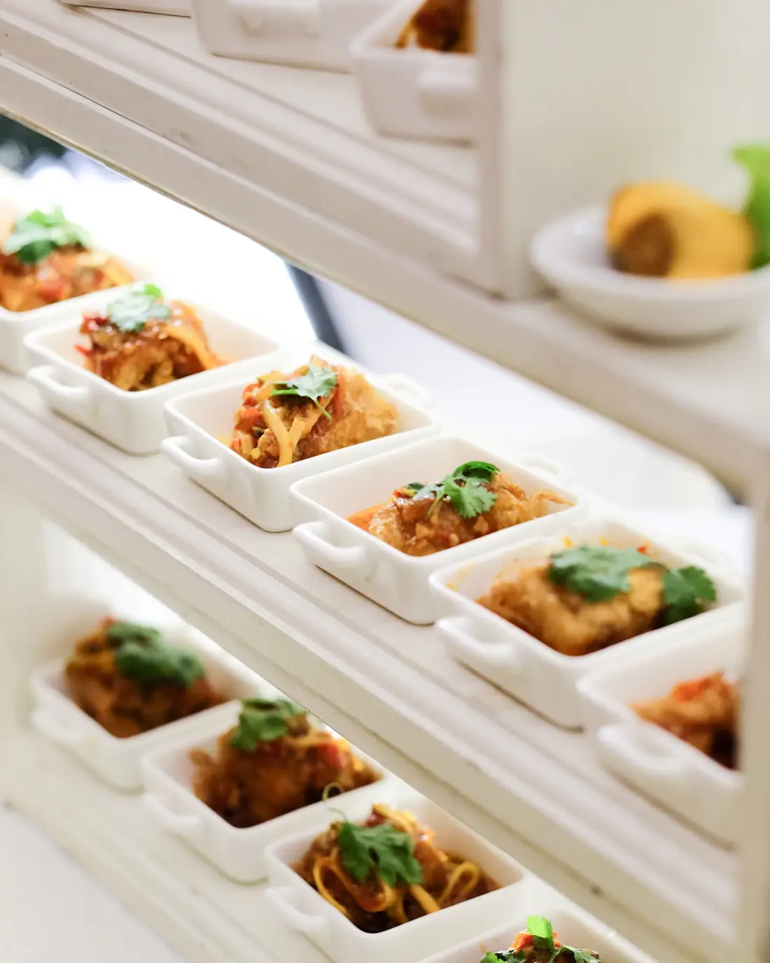Single portions plated in white dishes on a serving counter